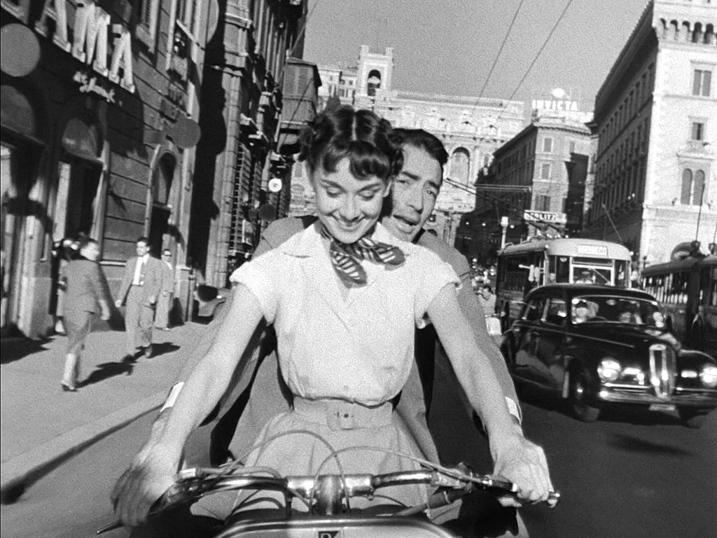 1024px-Audrey_Hepburn_and_Gregory_Peck_on_Vespa_in_Roman_Holiday_trailer.jpg